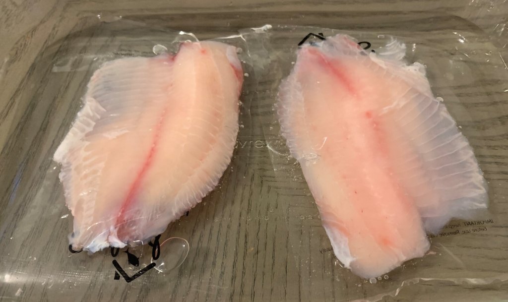 Picture of the frozen tilapia thawing in water (in a casserole dish).